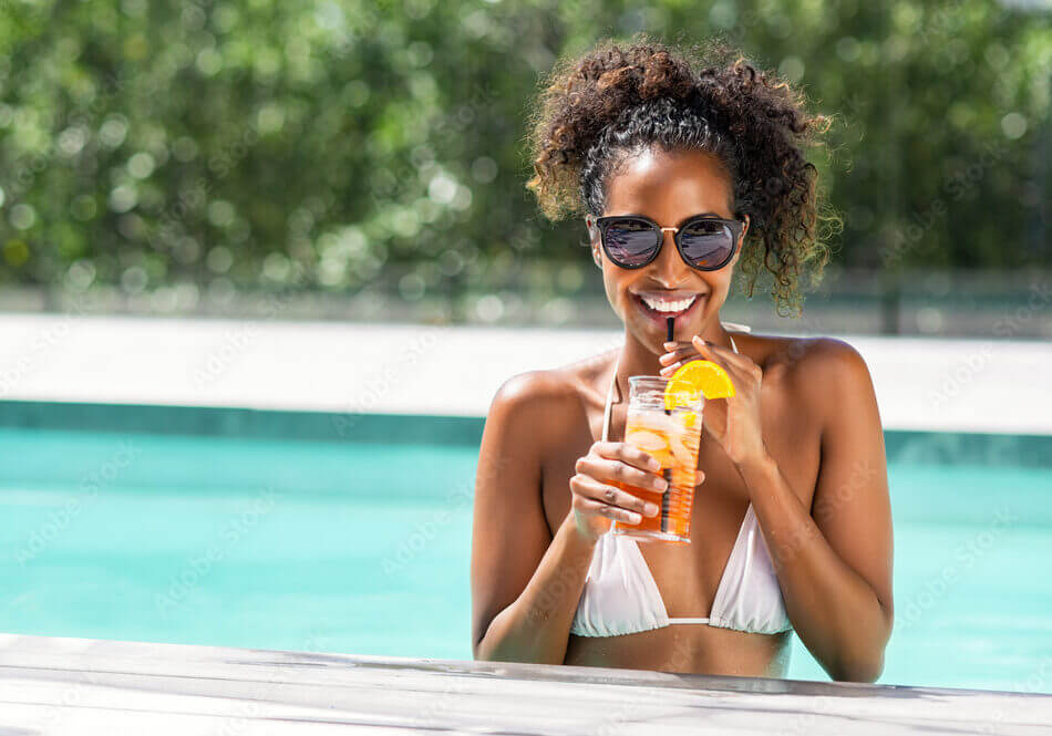 Fashion beauty woman in pool drinking cocktail