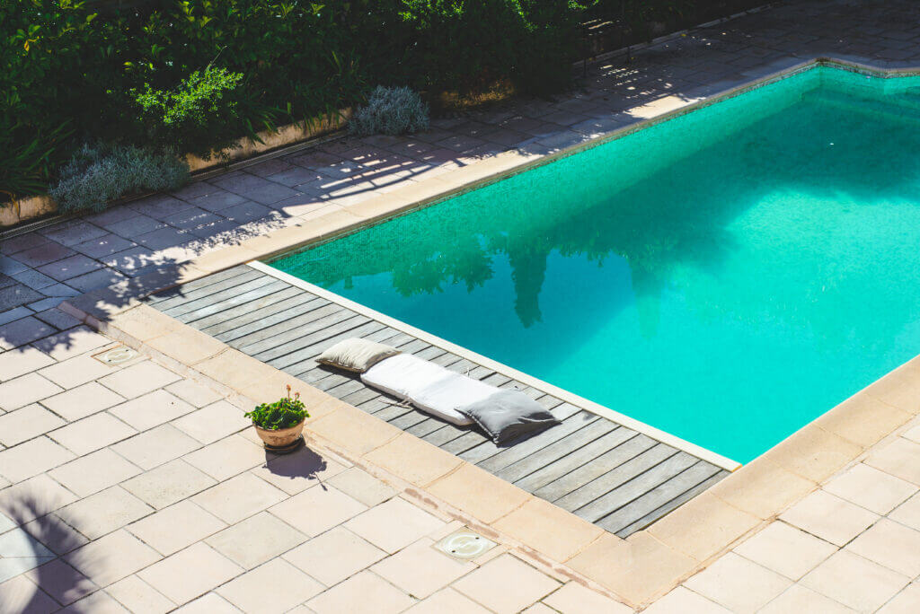 Pool with tiled area and small wooden lounging deck.